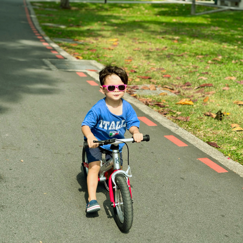 a little boy riding a KOKUA Jumper 12 bike down a street