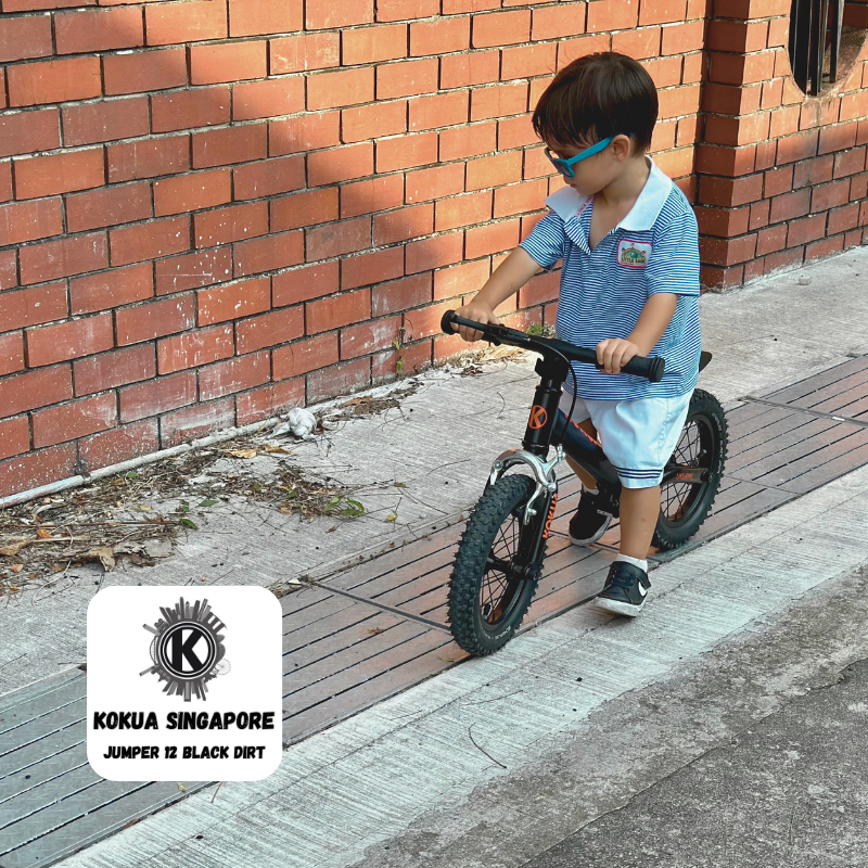 a young boy riding aKOKUA Jumper 12 balance bike on a sidewalk