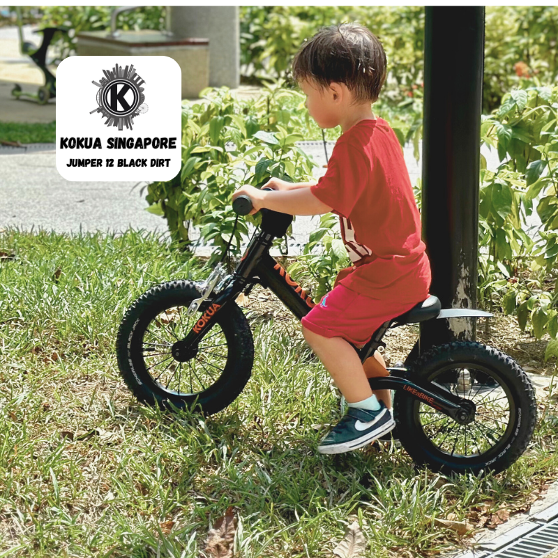 a young boy riding a KOKUA Jumper 12 balance bike in the grass