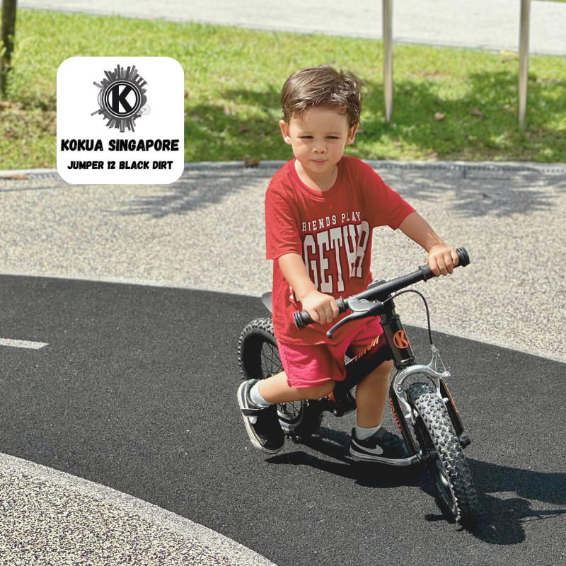 a young boy riding aKOKUA Jumper 12 balance bike on a playground