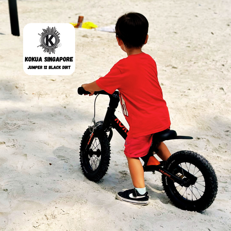 a young boy riding a KOKUA Jumper 12 balance bike on a sandy beach