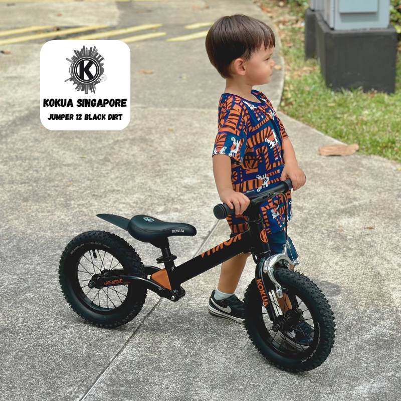 a young boy riding a KOKUA Jumper 12 balance bike on a sidewalk