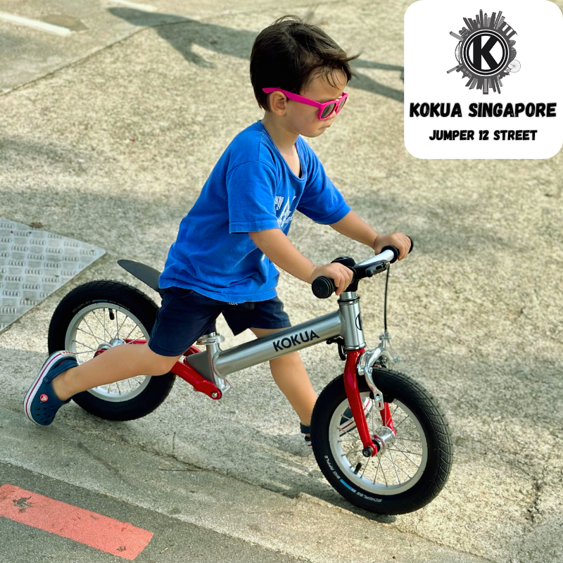 a young boy riding a KOKUA Jumper 12 balance bike down a sidewalk