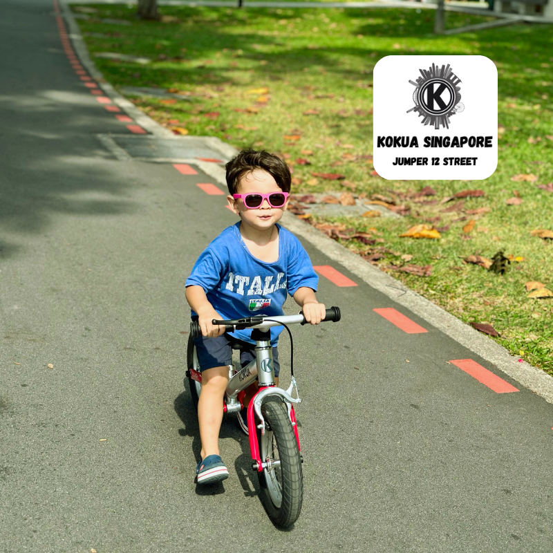 a young boy riding a KOKUA Jumper 12 balance bike down a street