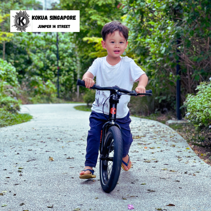 a young boy riding a KOKUA Jumper 14 balance bike down a dirt road