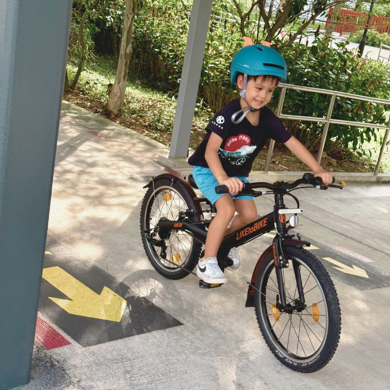 A boy riding the KOKUA LtB 20 SR in black on a Singapore park connector
