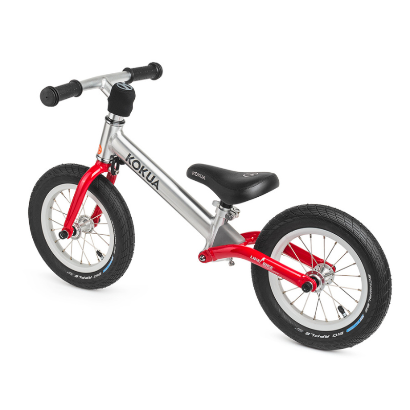 a red and black KOKUA Jumper 12 balance bike on a white background