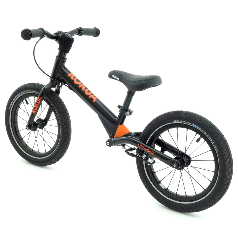 a black and orange KOKUA Jumper 14 balance bike on a white background