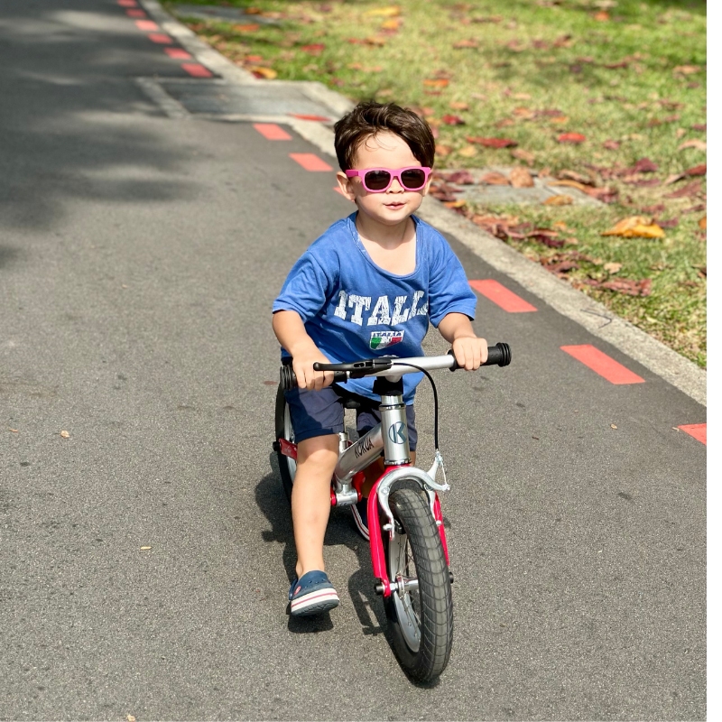 a young boy riding a KOKUA Jumper 12 balance bike down a street