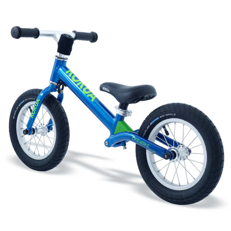 a blue and green KOKUA Jumper 12 balance bike with a black seat